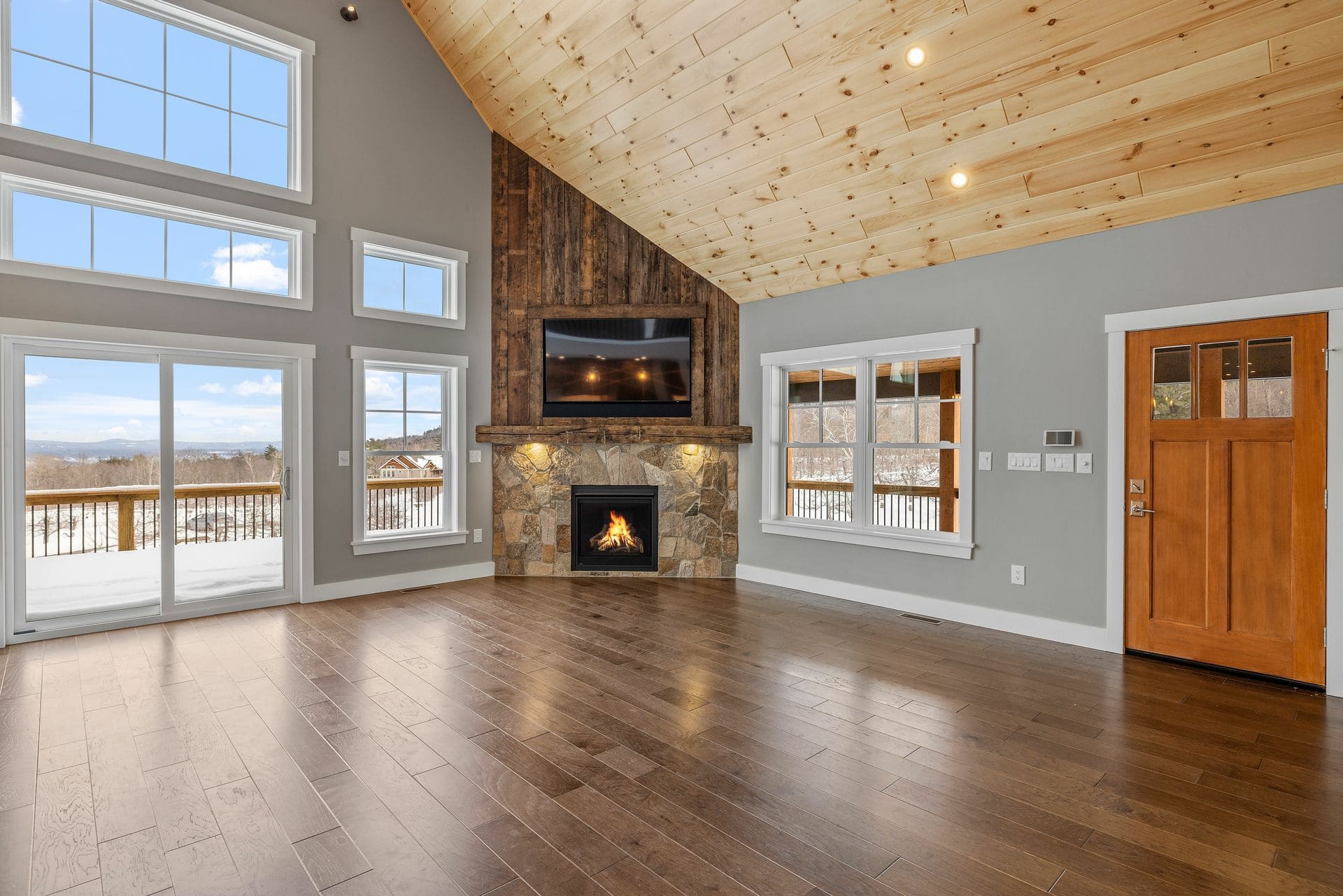 Modern great room with fireplace, wood ceiling, and mountain views through large windows